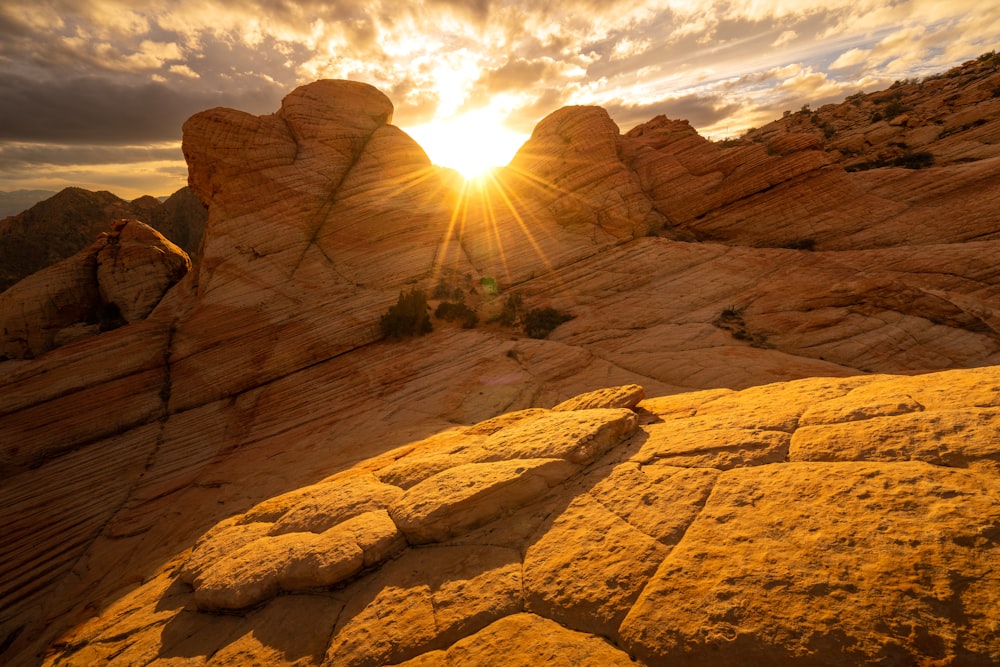 the sun is setting over the rocks in the desert