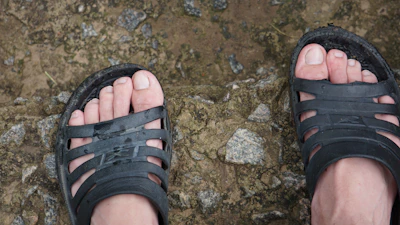 Close-up of sporty sandals with adjustable straps on a rocky trail.