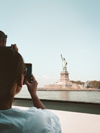 a man taking a picture of the statue of liberty