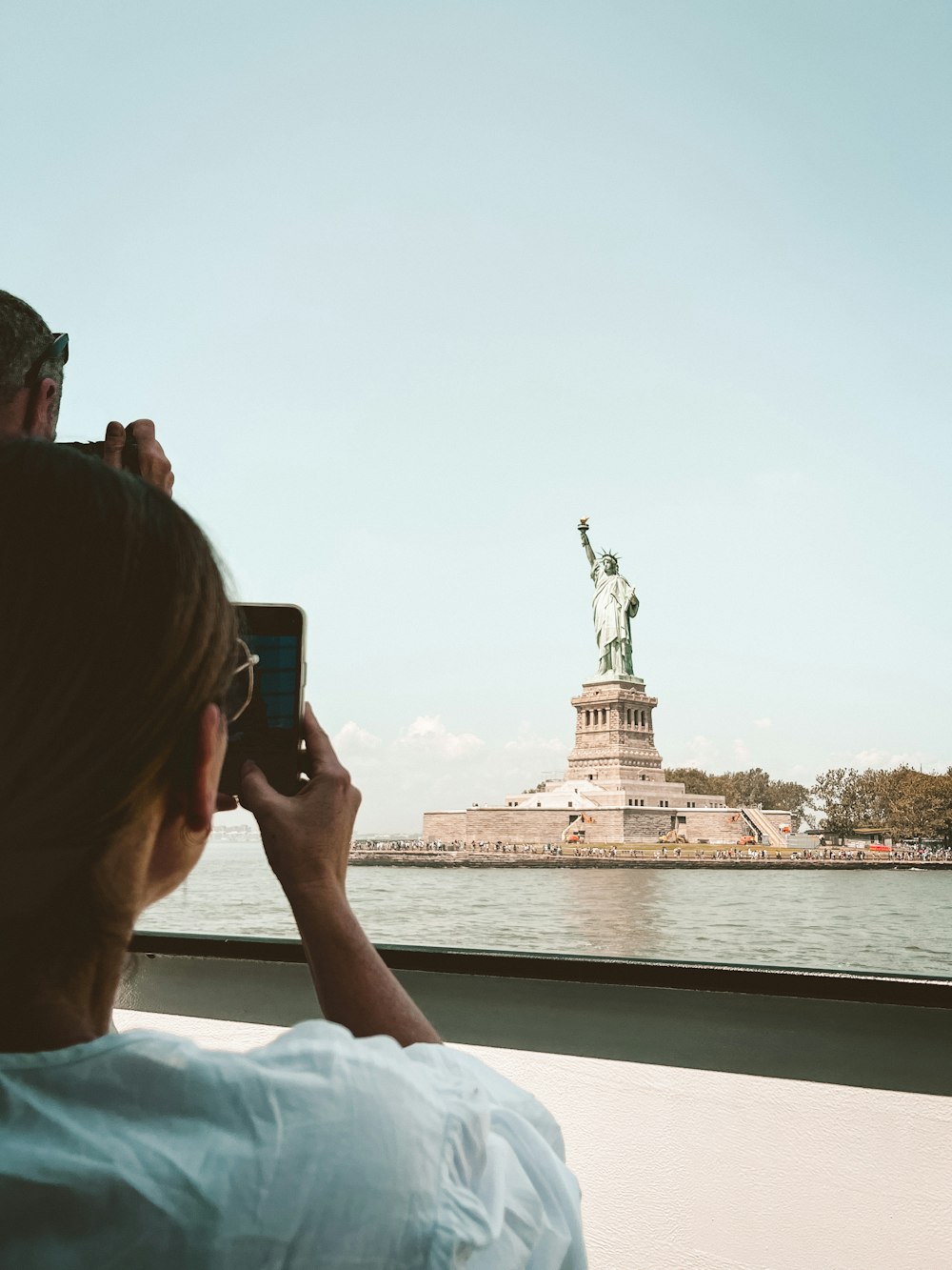 a man taking a picture of the statue of liberty