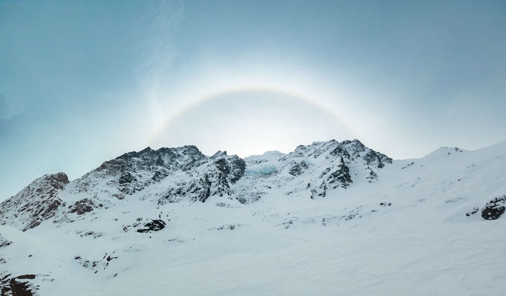 a snow covered mountain with a rainbow in the sky