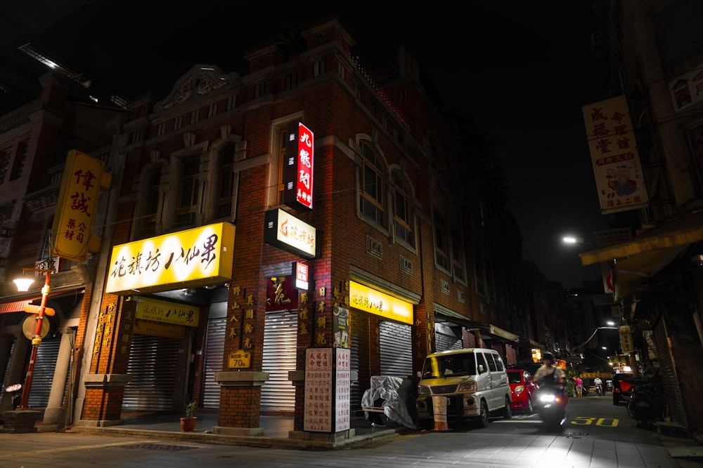 a city street at night with cars parked on the side of the street