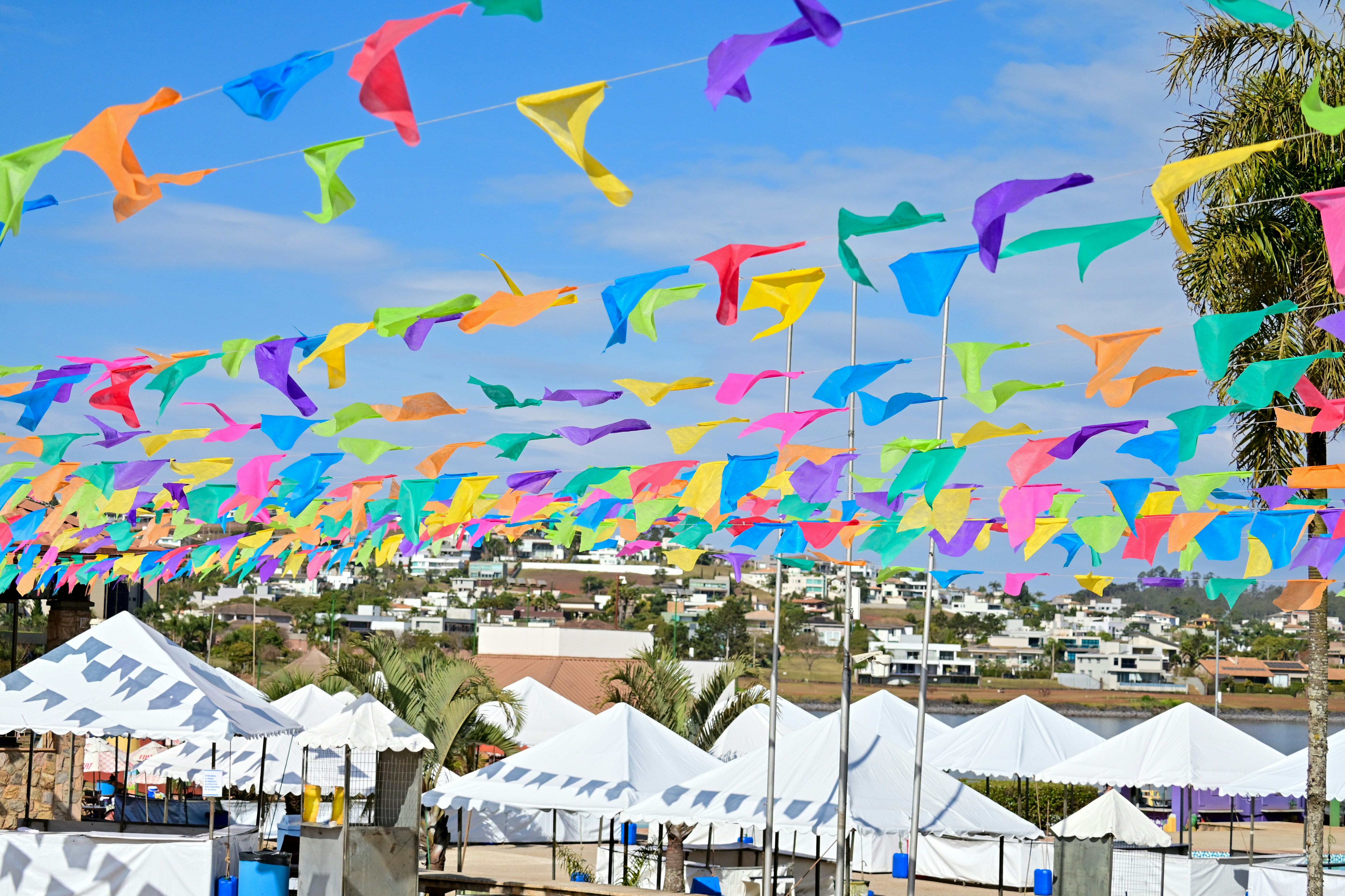 a bunch of kites that are in the air, The vibrant Brazilian Junino festival is adorned with colorful balloons, flowers, flags, and captivating decorations.