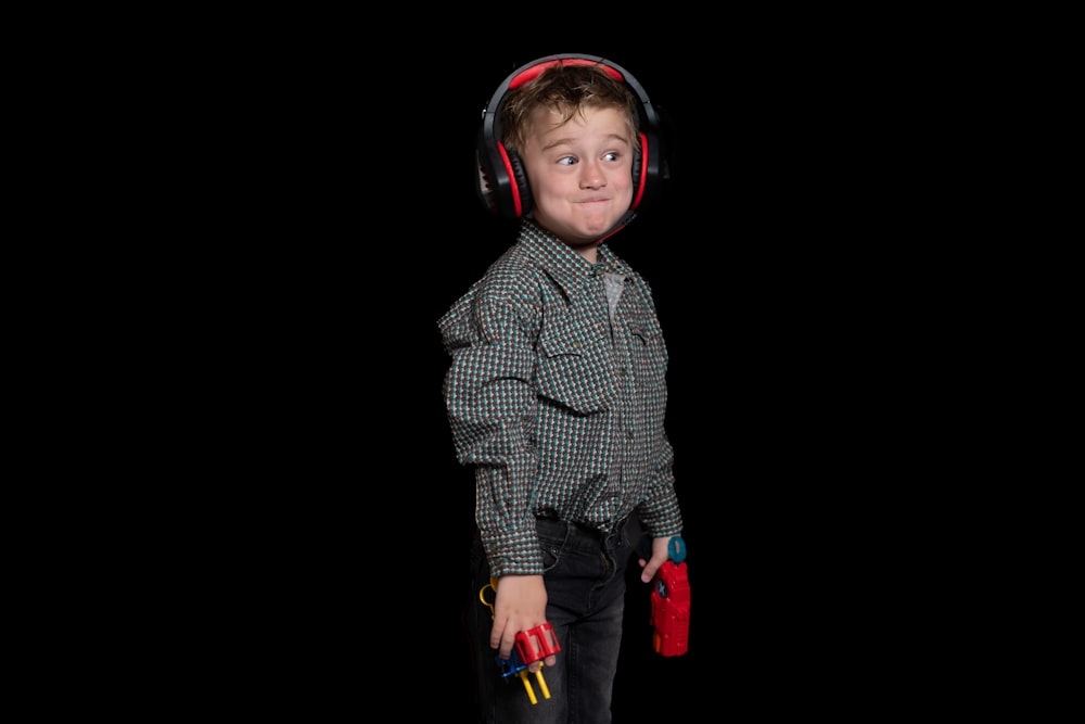 a young boy wearing headphones and holding a pair of red gloves