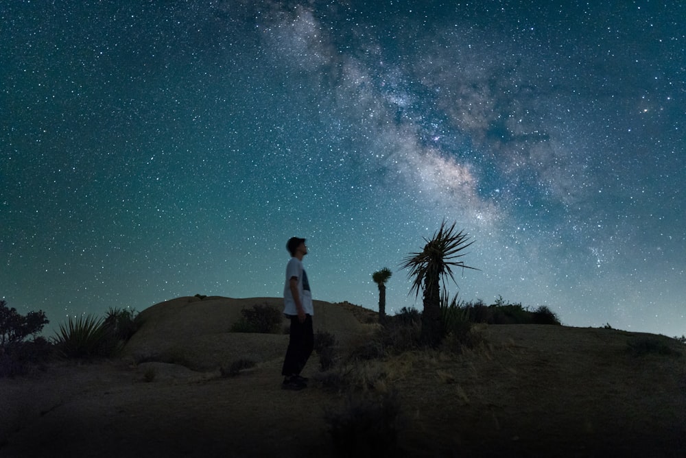 밤하늘 아래 사막 위에 서 있는 남자