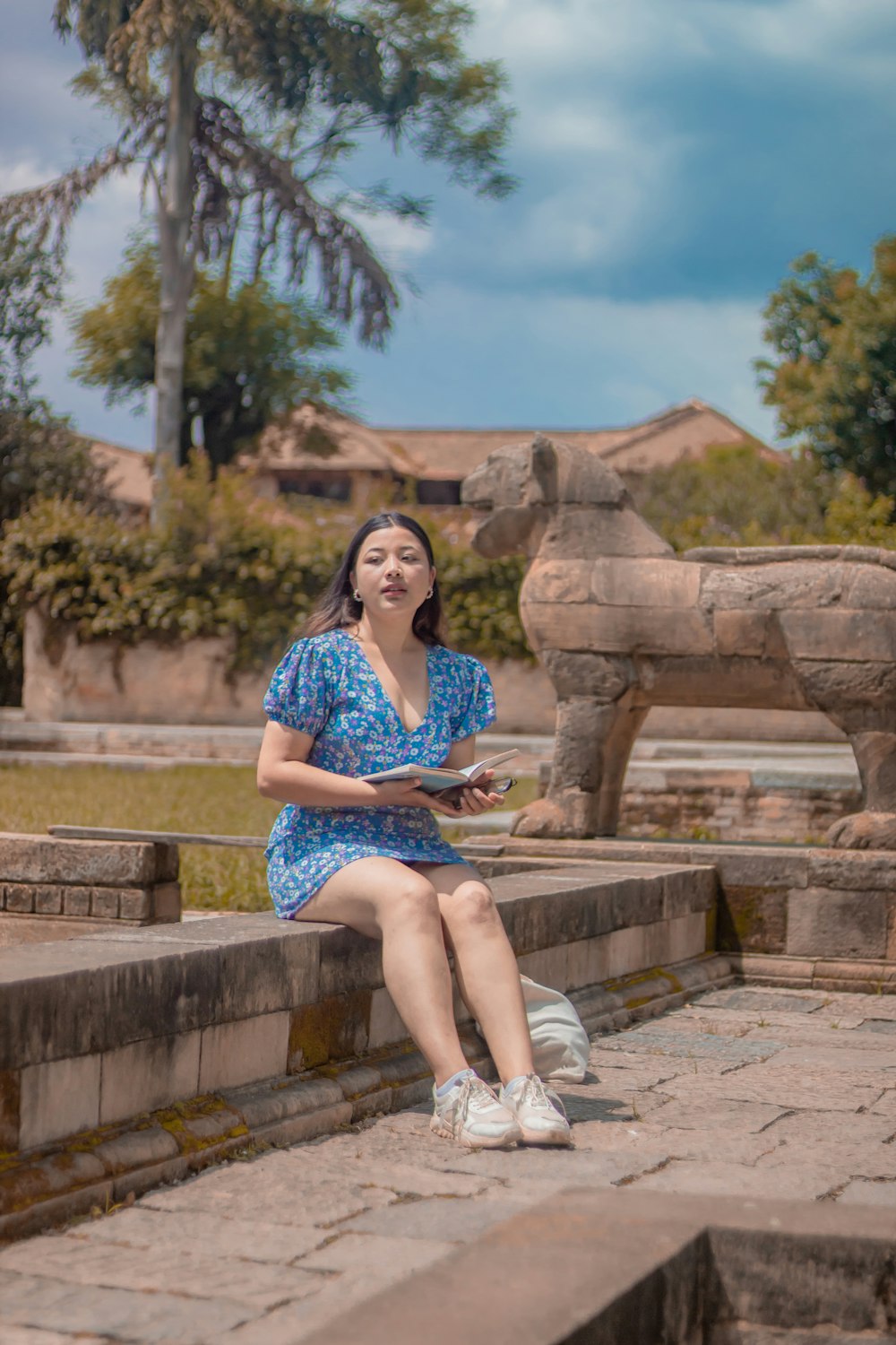 a woman in a blue dress sitting on a stone bench