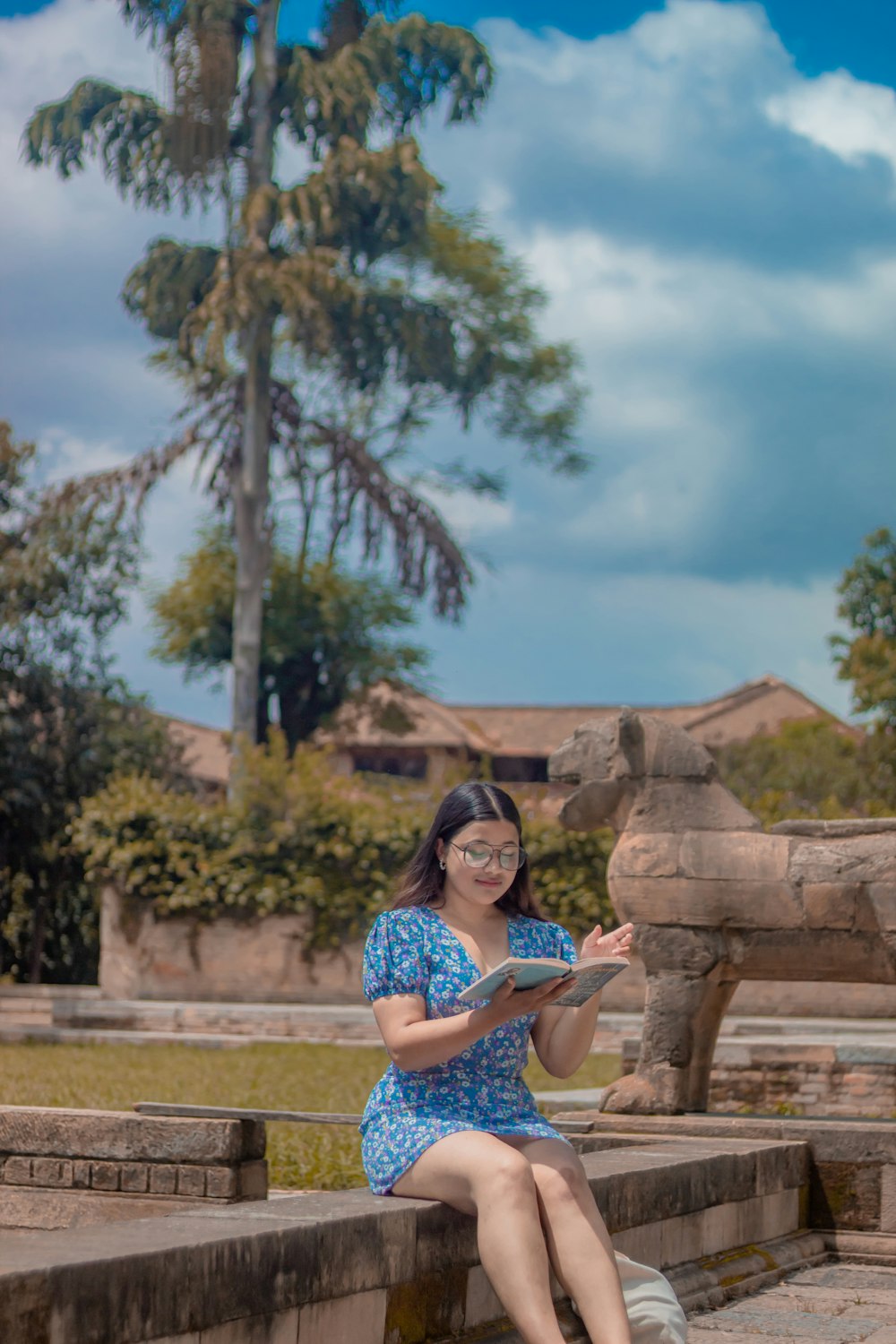 a woman sitting on a stone bench reading a book