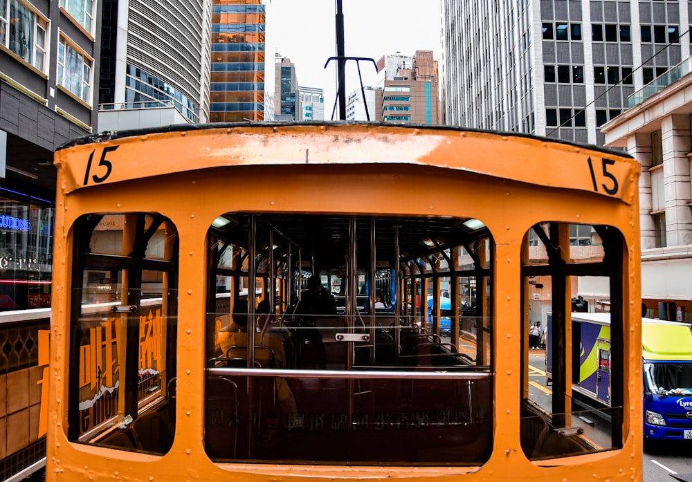 a yellow trolley car traveling down a street next to tall buildings