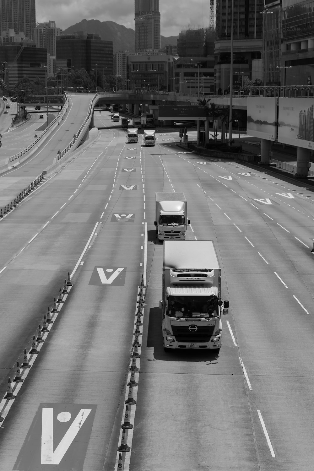 uma foto em preto e branco de dois caminhões dirigindo por uma rodovia