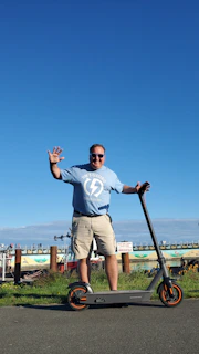 Smiling customer holding a fully restored electric scooter battery outdoors.