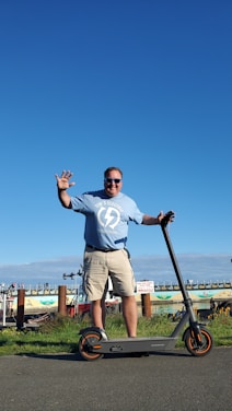 A smiling customer using a mobility scooter outdoors on a sunny day.