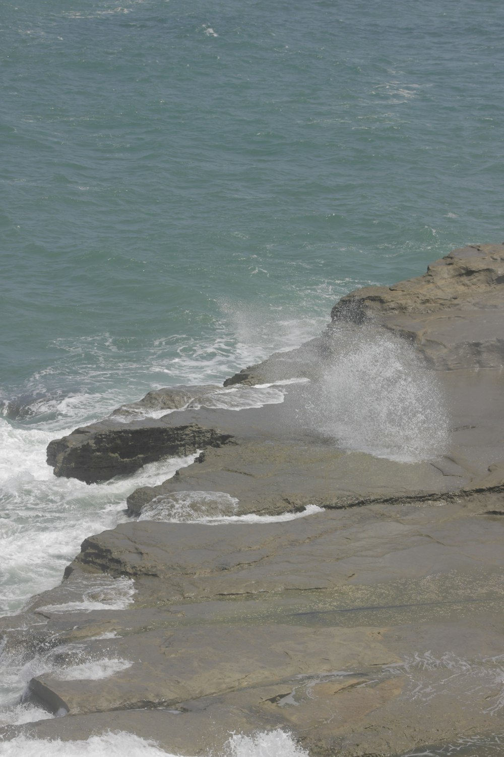 a person standing on a rocky beach next to the ocean