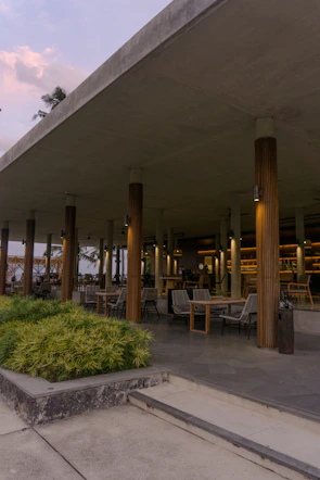 An open-air communal space with natural wood and stone elements blending with tropical plants.