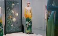 A finished hand-painted dress displayed on a mannequin, glowing with warm, earthy tones.