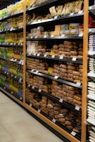 Shelves in a grocery store are stocked with various packaged food items. The left side features a range of cooking oils, while the right side displays a selection of baked goods or packaged snacks. Each shelf is orderly, with products neatly arranged in rows and labels visible for pricing.