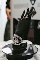 a hand with a ring on top of a black plate