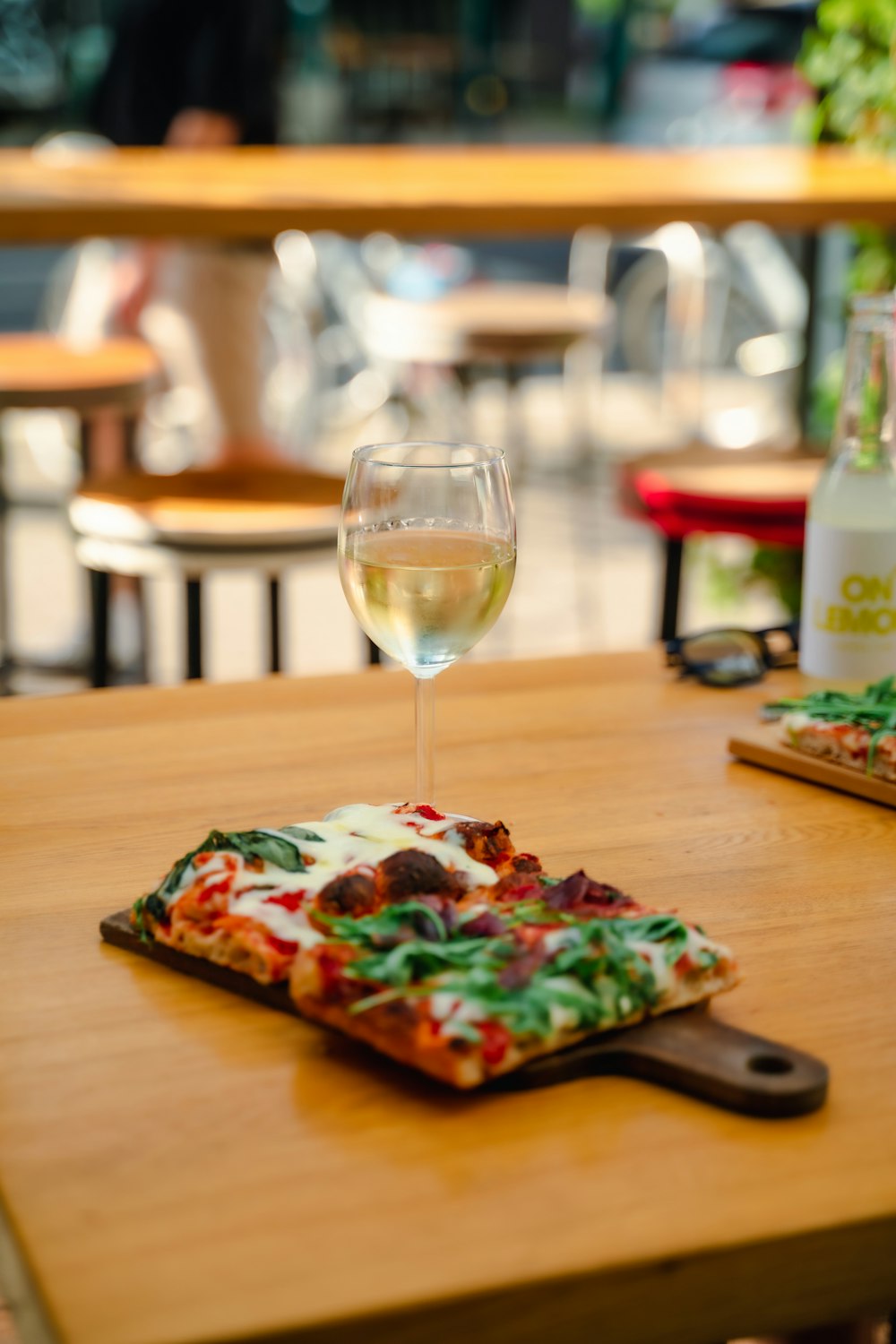 a wooden table topped with a pizza and a glass of wine