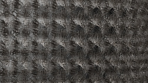 An intricate metallic mesh pattern with repeating, interconnected loops and curves, creating a visually dense and complex texture.