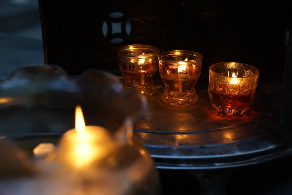three lit candles sitting on top of a metal tray