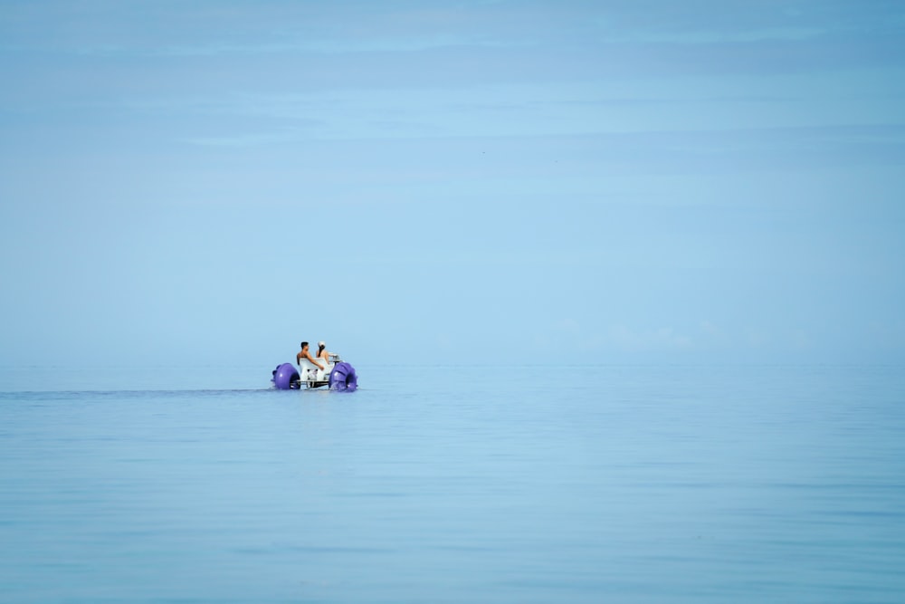 two people on a small boat in the middle of the ocean