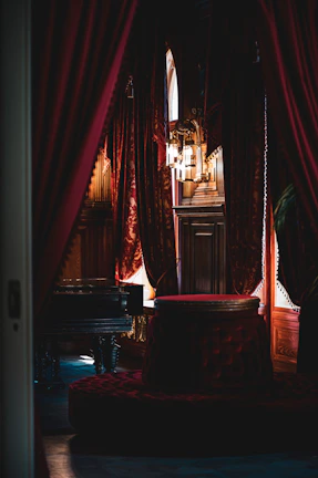 A dimly lit Victorian parlor with velvet drapes and ornate candle holders casting shadows.
