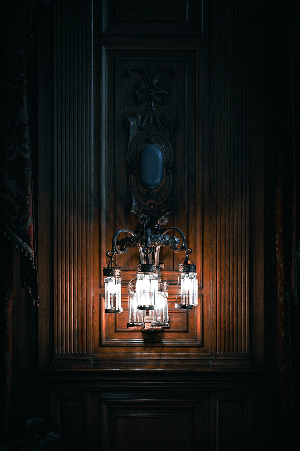 a chandelier in a dark room with a mirror on the wall