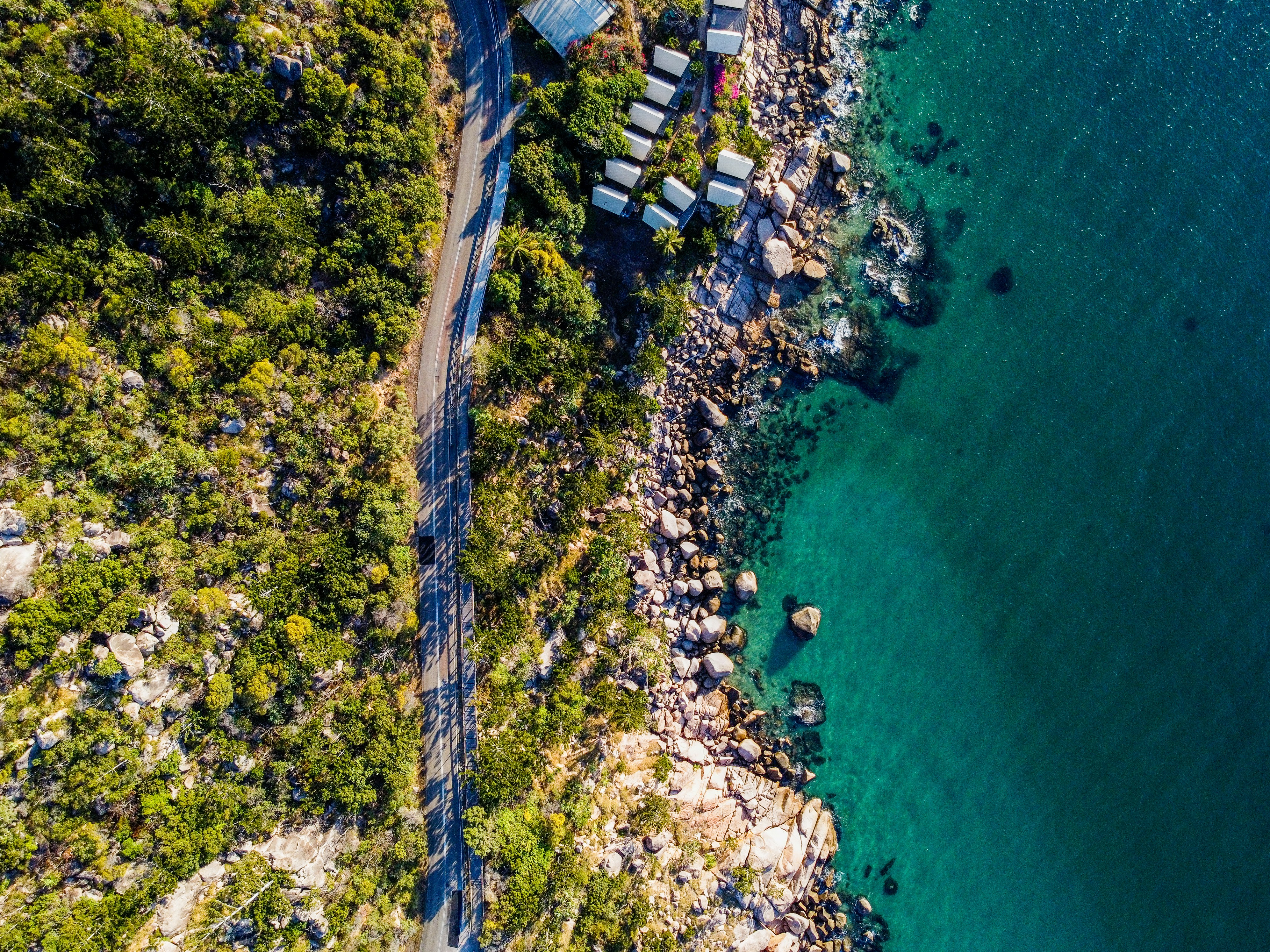 an aerial view of a road next to a body of water