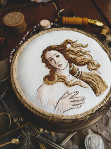 Close-up of a delicate thread art portrait framed in natural wood, highlighting intricate details.