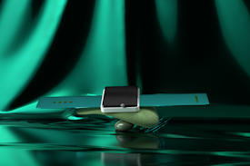 A modern smartwatch with a sleek black screen and turquoise strap is artfully balanced atop a smooth, textured stone. The background features a luxurious, shimmering green fabric, adding a glamorous aesthetic to the composition.