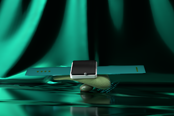 A modern smartwatch with a sleek black screen and turquoise strap is artfully balanced atop a smooth, textured stone. The background features a luxurious, shimmering green fabric, adding a glamorous aesthetic to the composition.