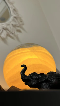 A cozy corner featuring a wooden animal figurine beside a softly glowing lamp.