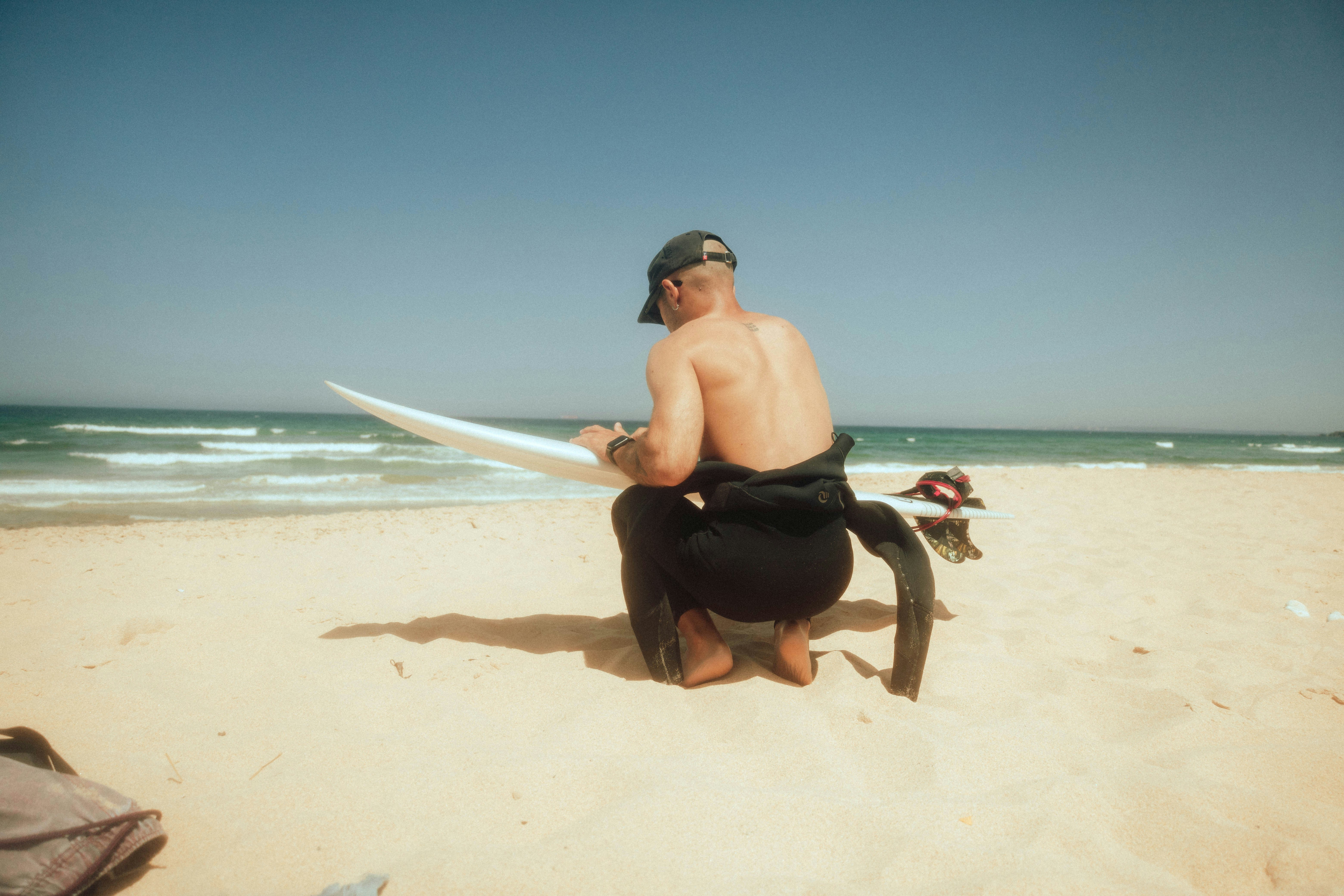 a man sitting on a beach holding a surfboard