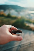 A hand holding a rustic, handmade clay cup against a soft natural background.
