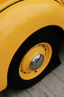 Close-up of a polished yellow sports car wheel reflecting sunlight.