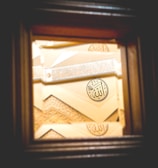 A detailed piece of Islamic geometric art featuring Arabic calligraphy. The artwork includes intricate patterns and a prominent circular motif with calligraphy in the center.