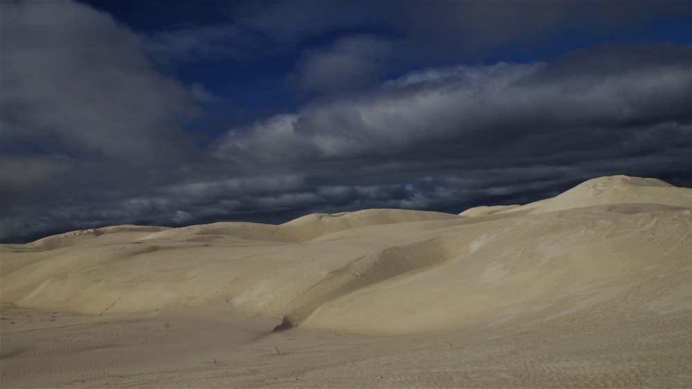 a large group of sand dunes under a cloudy sky