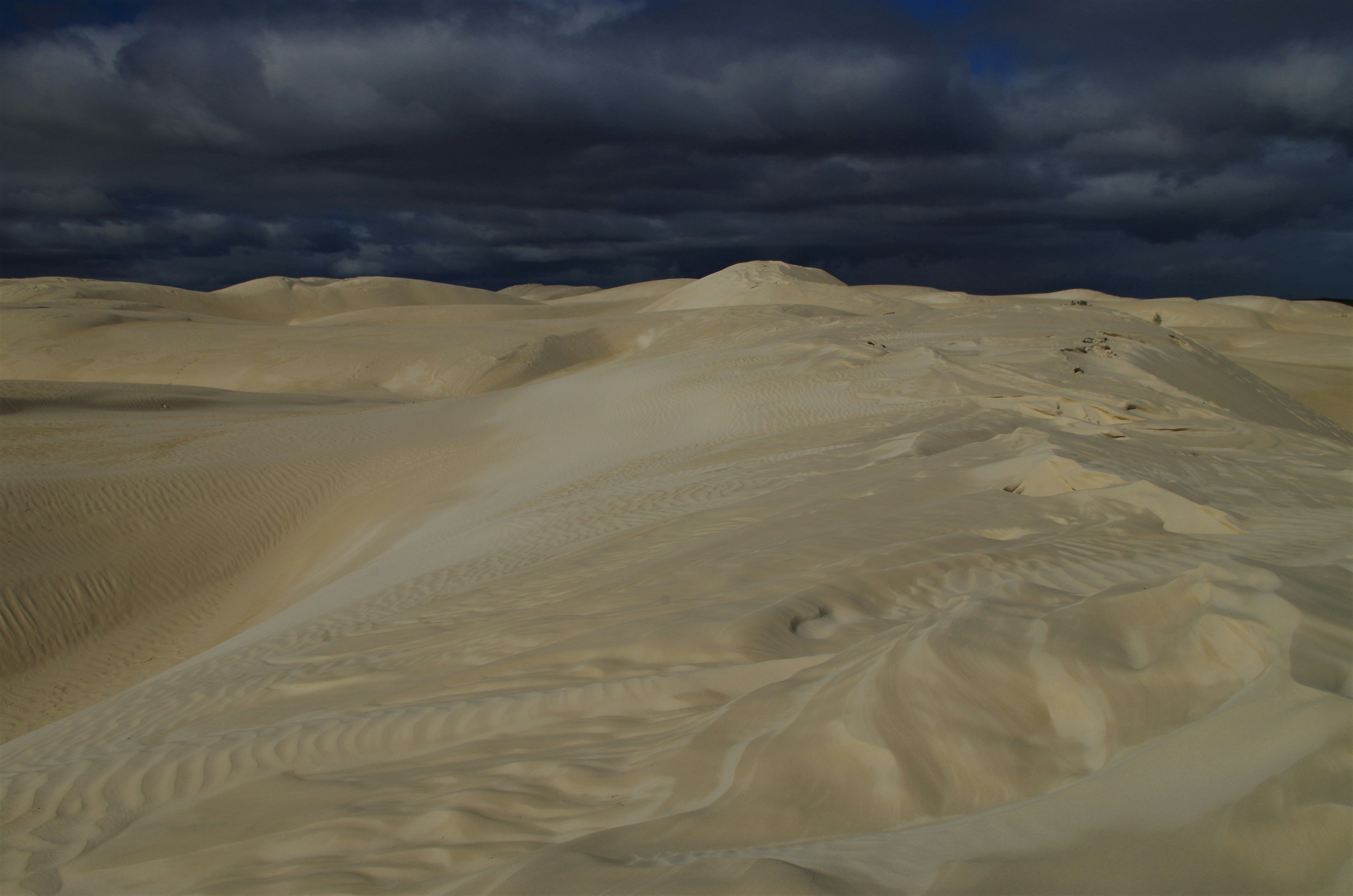 un grand groupe de dunes de sable sous un ciel nuageux
