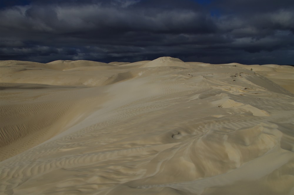 a large group of sand dunes under a cloudy sky