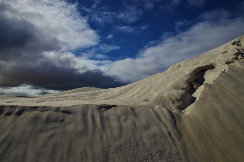 a large sand dune with clouds in the background