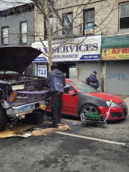 A roadside assistance vehicle helping a stranded car with a mechanic inspecting the engine.