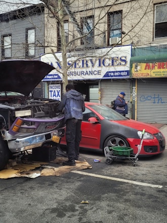 A mechanic assisting a driver with a car engine issue on the roadside.