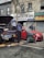 A roadside assistance vehicle parked beside a broken-down car, with a technician inspecting the engine.