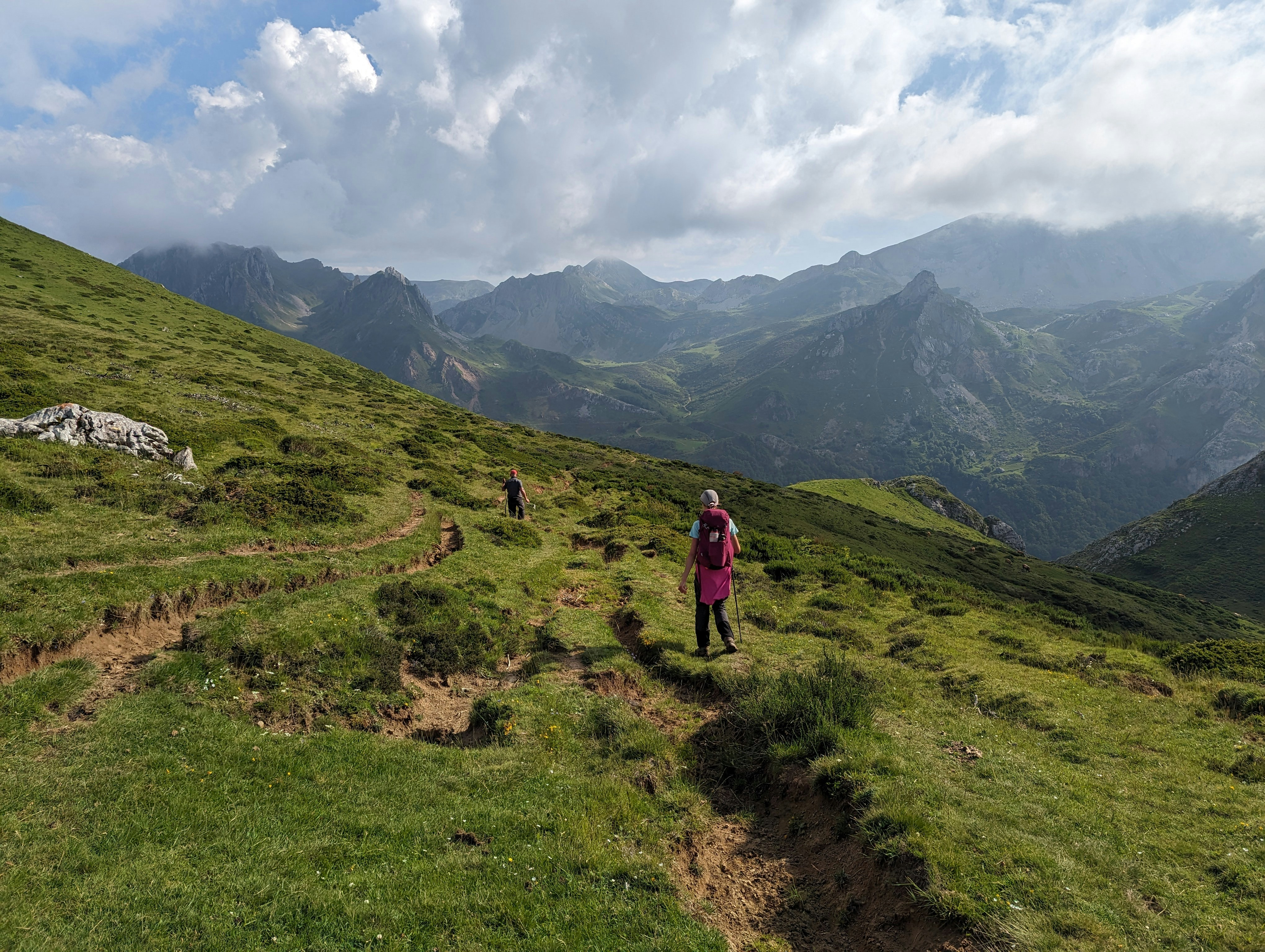 Couple hiking in the lush green hills of Manali with clear blue skies.