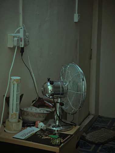 A tall, oscillating tower fan standing in a bright living room corner near a window.