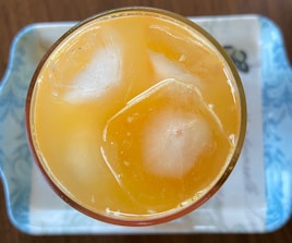 Close-up of a glass filled with colorful fresh fruit juices and ice cubes.