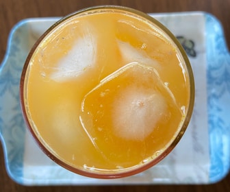 Close-up of a glass filled with colorful fresh fruit juices and ice cubes.