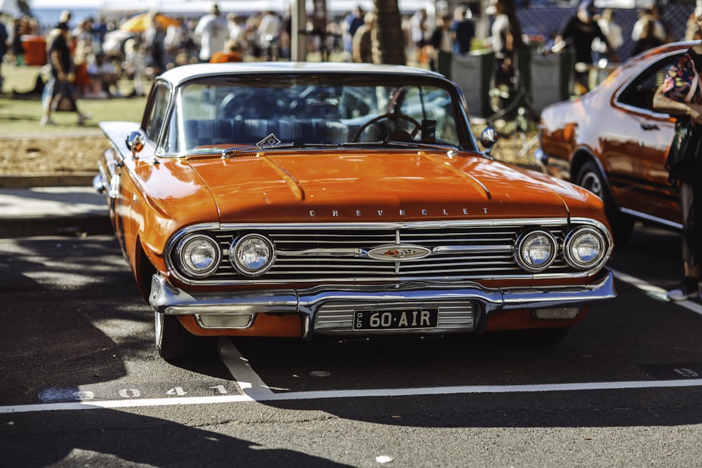 Um carro clássico laranja estacionado em um estacionamento