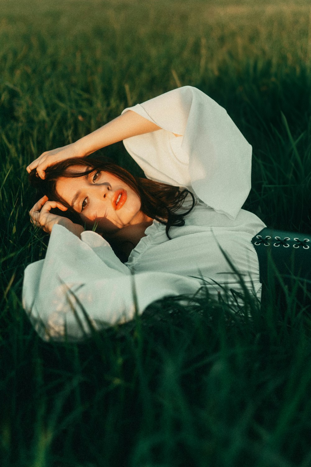 a woman laying in the grass in a white dress