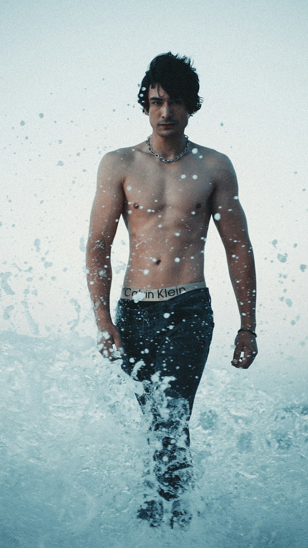 a shirtless man walking through the water