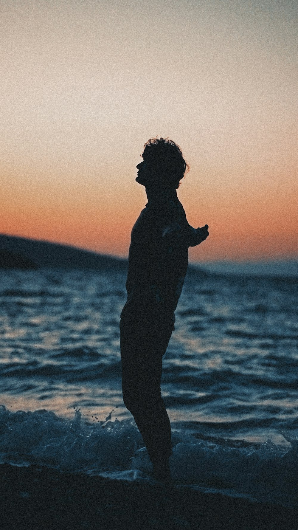 a person standing in the water at sunset